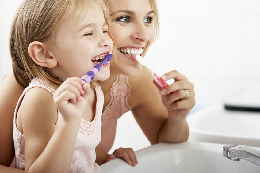 Mother And Daughter Brushing Teeth Together